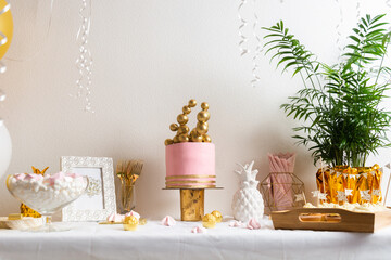 Holiday birthday table with cake and ballons. Pink and golden decoration