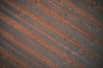 Striped texture brown red color aerial view. Texture of arable land top view. Winter texture plowed land drone view. Italian arable land in winter season top view.