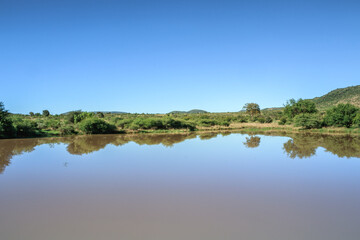 Landscape view of a lake surrounded by mountains and green savanna grassland, Pilanesburg Nature Reserve, North West Province, South Africa