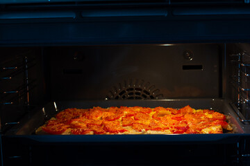 Juicy meat with potatoes, tomatoes and cheese is in the oven