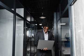 Focused young black businessman working online on laptop in office. Remote work