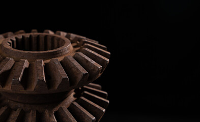 Parts of an old mechanism made of metal gears and other parts covered with rust on a black...