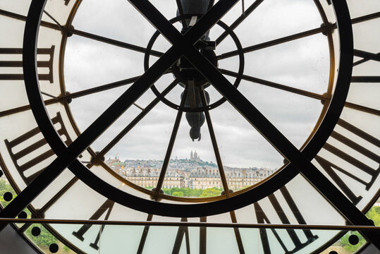 View of church Sacre Coeur in Montmartre through a large Clock from Museum d'Orsay in Paris
