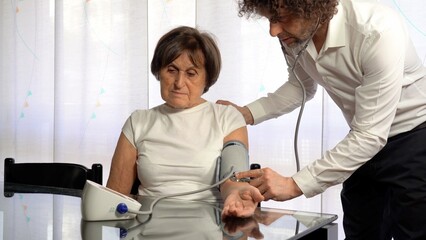 70 year old old lady woman tests blood pressure at home - private doctor visit in apartment  during...