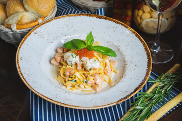 Traditional Italian pasta Carbonara with salmon and red caviar on a plate 