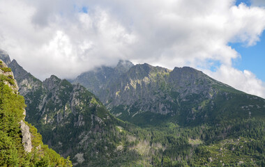 Sharp rocky high ridges of mountain ranges covered with trees and vegetation under a cloudy sky. High Tatras, Slovakia