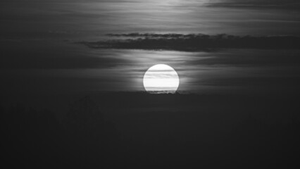 Beautiful wild sunrise and cloudy sky. The sun behind the clouds. Black and white picture