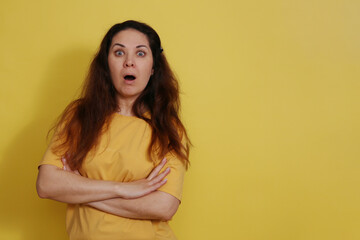 Fototapeta premium Close up portrait of a surprised woman in a yellow t-shirt on a studio background.