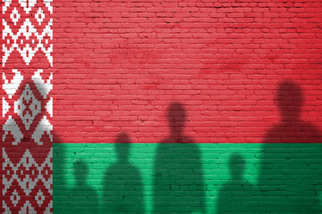 The refugees migrate to Europe union . Silhouette of illegal immigrants . Europe union migration policy. Flag of Belarus painted on a brick wall