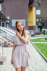 Fototapeta premium Young happy woman walks around city on summer day. Dressed in light dress