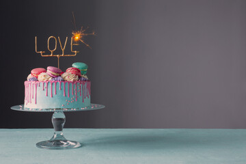 cake with pink and blue decor and sparkler with text love