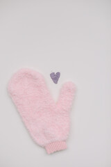 Minimal flat lay composition of massage mitten washcloth and a heart made of violet powder on a white background. Concept of zero waste
