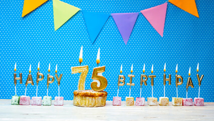 Happy birthday from number 75 candle letters on a blue background with white polka dot copy space....