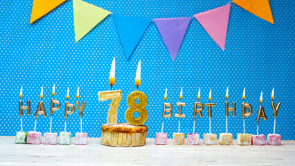 Happy birthday from number 78 candle letters on a blue background with white polka dot copy space....