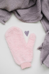 Minimal flat lay composition of massage mitten washcloth and a heart made of violet powder on a white background. Concept of zero waste
