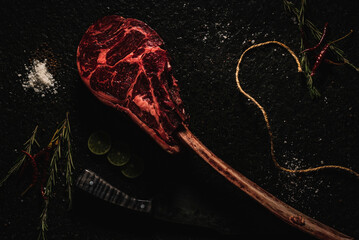 corte de res  TOMAHAWK  sobre laja de piedra  con decoración como sal, pimienta limón, chile de...