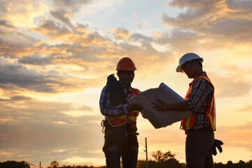 Engineering Consulting People on construction site holding blueprint in his hand