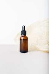 Naklejka premium Serum glass bottle with pipette on the beige wrinkle paper background. Natural Organic Spa Cosmetic concept. Front view. Place for your text.