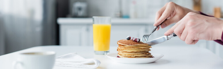 partial view of man cutting pancakes near orange juice and coffee cup, banner.