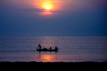 silhouettes of people on the beach at sunset
