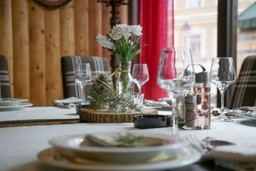 Simple and elegant table setup with dinner set and bouquet o f white flowes. Emty restaurant tables...