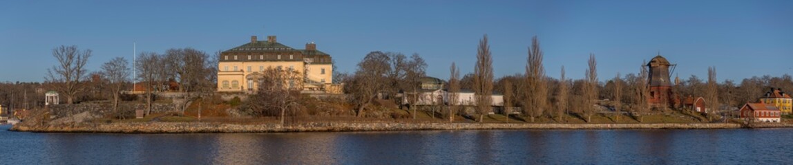 Fototapeta na wymiar Panorama view of the ness Waldemars Udde, prince Eugens art museum, a gazebo and the old oil mill on the island Djurgården a sunny winter day in the archipelago of Stockholm