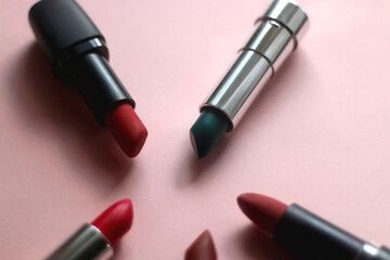 Lipsticks in various shades and colors on bright pink background. Selective focus.