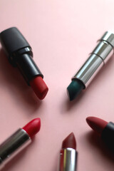 Lipsticks in various shades and colors on bright pink background. Selective focus.