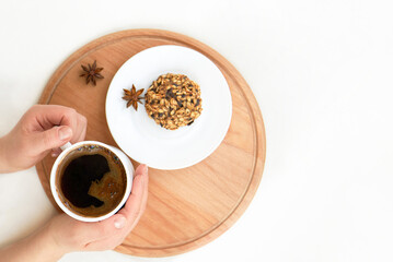 Woman's hands with a cup of coffee on a wooden tray on a light background.