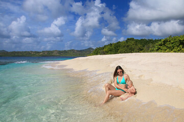 Mother with a baby sitting at the beach, White Island near Carriacou Island, Grenada.