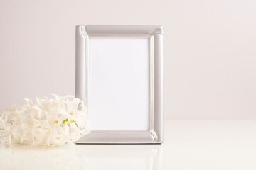 Fototapeta na wymiar Mockup photo frame with a beautiful white hyacinth flower on the table. Template for design.