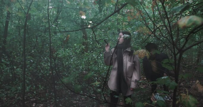Woman uses flashlight to navigate misty forest 