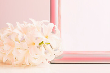 Mockup photo frame with a white hyacinth flower on the table. Neon lighting, closeup. Template for design.