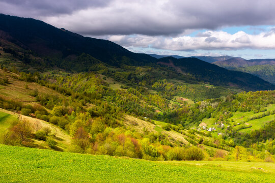 mountainous countryside in spring. beautiful nature scenery with rolling hills, forested slopes and grassy valleys on a sunny morning with clouds on the sky