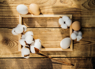 Eggs and a branch with white cotton flowers with sunny shadows on a wooden background.A holiday card.Easter Holiday.