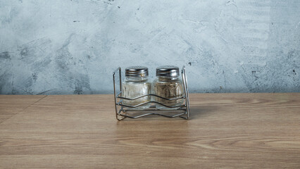 Modern Salt and Classic pepper grinders standing on wood texture table. Salt and pepper shaker on...