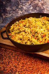 Healthy vegan food - vegetable pilaf from Indian cuisine, close up. Homemade delicious pilaf with beans, fresh parsley and ripe vegetables on a dark background close up. Top view