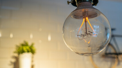 Efficient incandescent light bulb waste electricity against a tiled wall with a small bike and a...