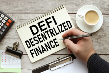 DEFI DESENTRLIZED FINANCE open notebook on the desktop with a calculator and a cup of coffee. male hand writes text