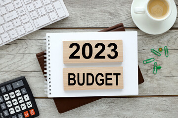 2023 BUDGET two wooden blocks on a brown notebook on a wooden table