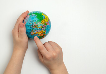 The globe in children's hands. Child's finger indicating a place on the globe. Children's education concept