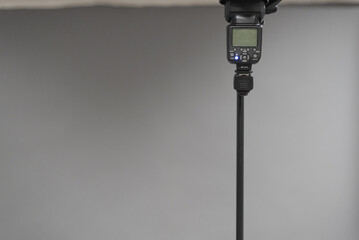Camera flash light on the tripod on the gray background.