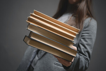Stack of books in the teacher or student hands close up.