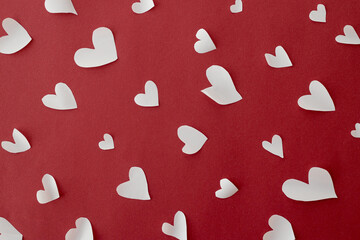 Happy Valentine's Day! Stylish hearts composition on red background flat lay. Valentines day card. Cute little white hearts cut outs on red paper. Love concept