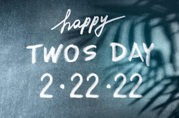 Happy Twos Day 2.22.22 vector concept. White chalk lettering on scholboard background with palm leaves shadows. February 22, 2022 is such an significant date.	