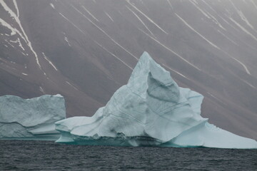 duża spiczasta góra lodowa na morzu u wybrzeży grenlandii w pochmurny dzień