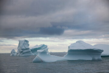 duże góry lodowe o różnych kształtach na morzu w pochmurny dzień - 482907918