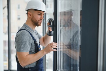 Construction worker repairing plastic window with screwdriver indoors, space for text. Banner design