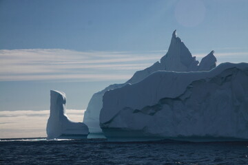 różnokształtne duże  góry lodowe na morzu w słoneczny dzień - obrazy, fototapety, plakaty