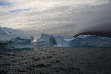 masywne bloki lodowe na morzu o zachodzie słońca - 482908713